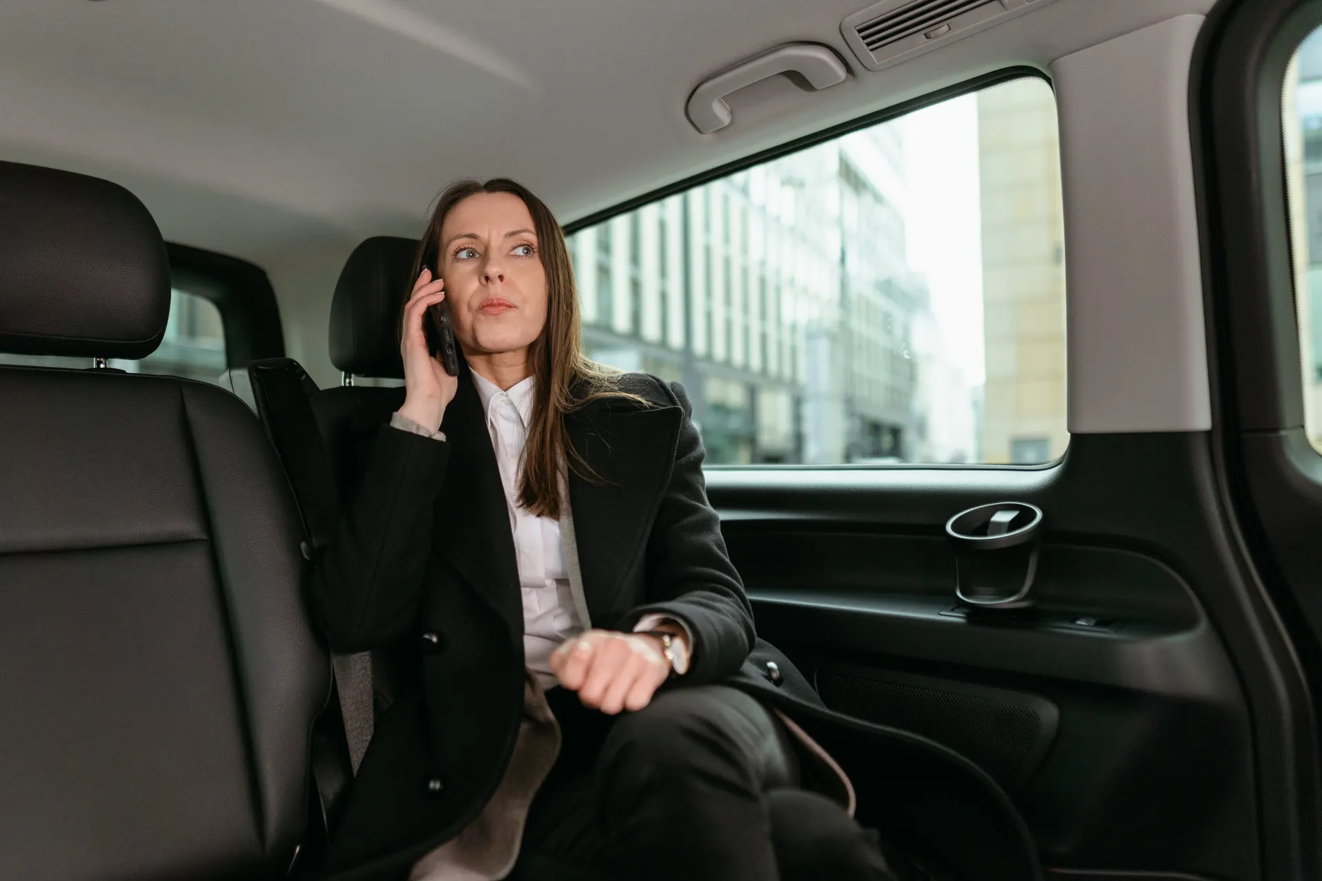 Collaboratrice en déplacement, assise dans sa voiture, au téléphone entre deux rendez-vous