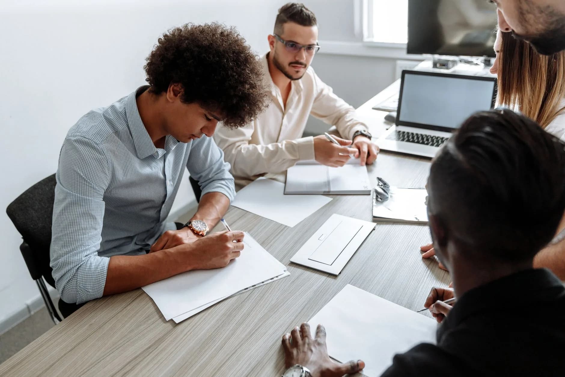 Équipe réunie autour d'une table de travail, avec prise de notes et ordinateurs portables