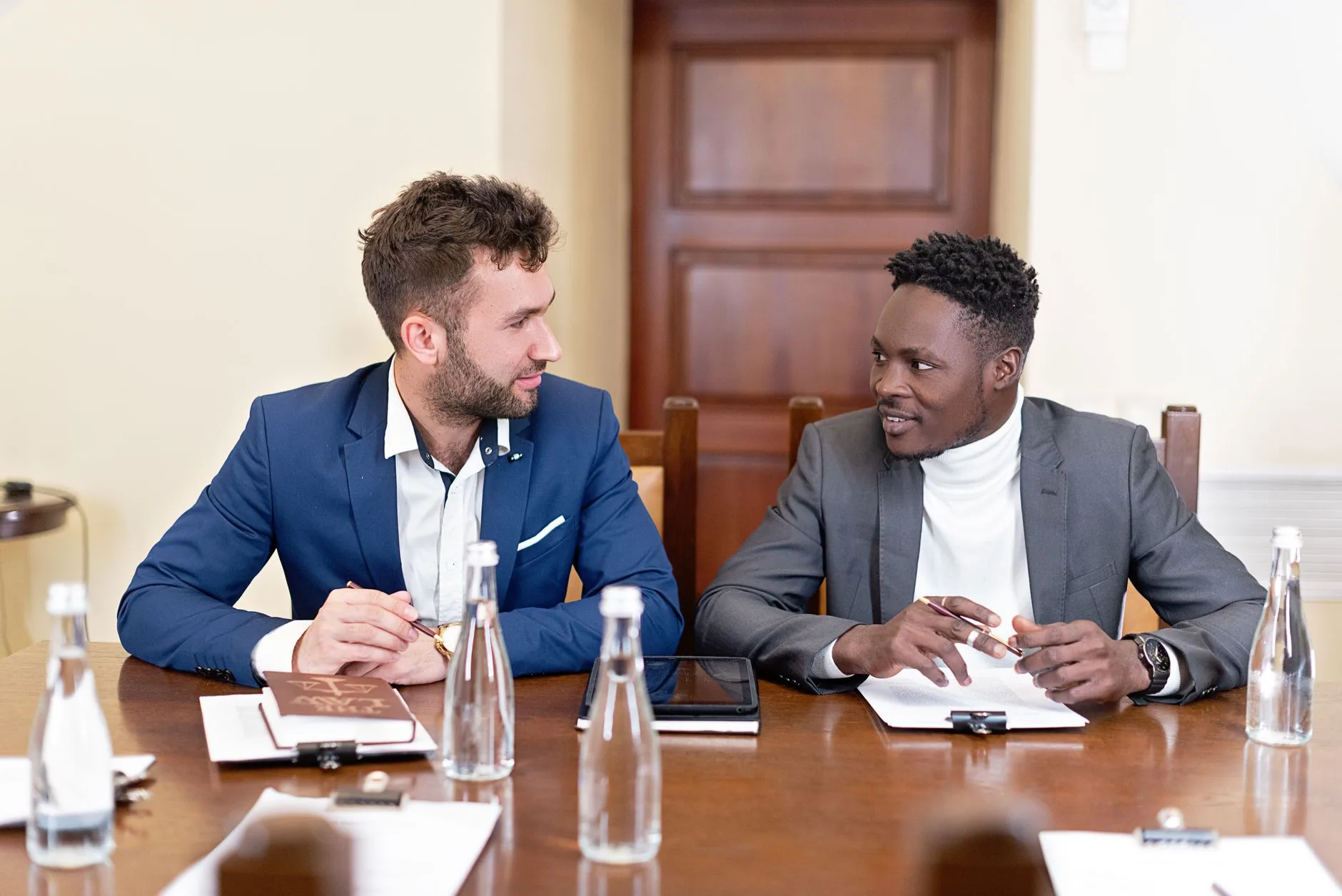 Deux dirigeants en costume discutent face à face autour d'une table de réunion