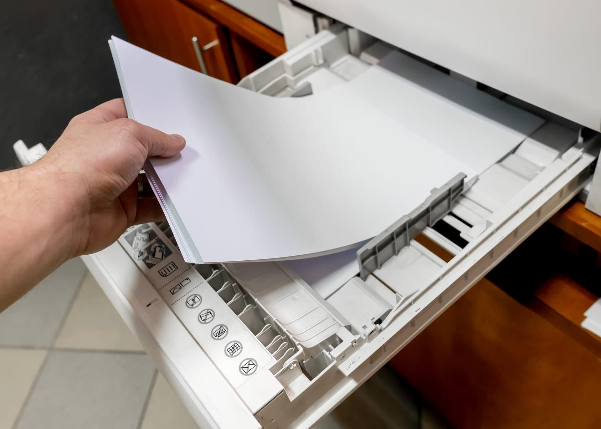 Main insérant une feuille de papier dans le bac d'un scanner de bureau