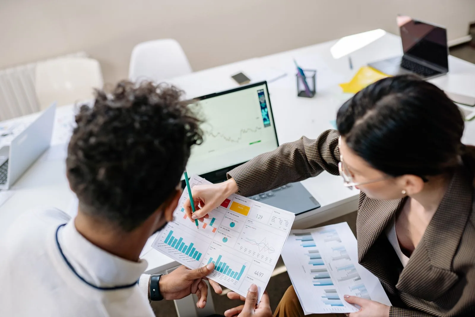 Deux collègues analysent des courbes de performance sur un ordinateur portable lors d'un point marketing