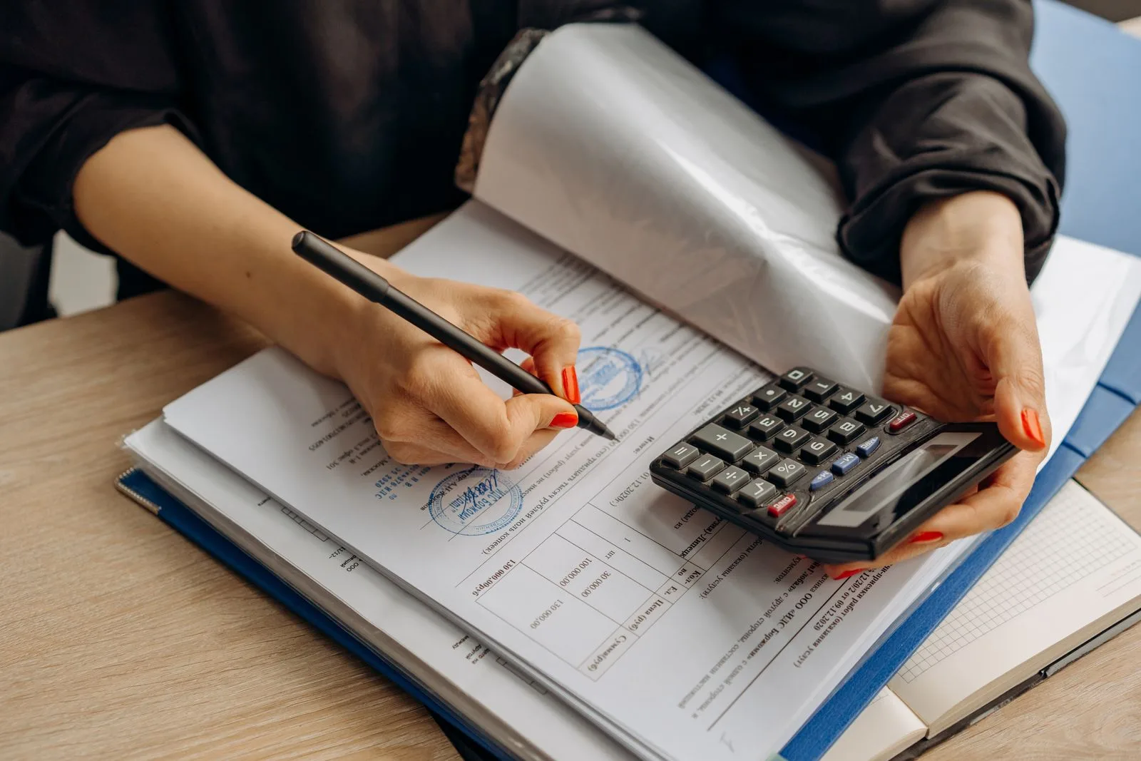 Vérification manuelle d'un formulaire fiscal tamponné, stylo et calculatrice à la main