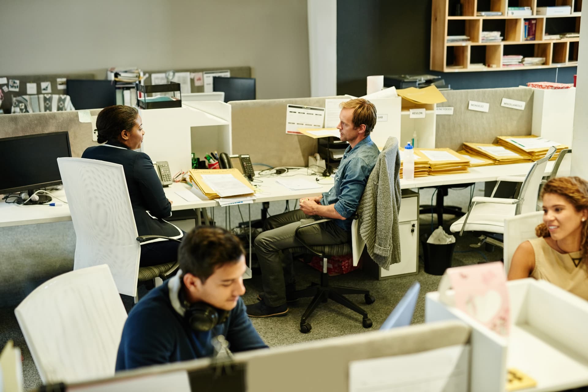 Bureaux d'une PME où dossiers papier et enveloppes s'empilent sur les postes