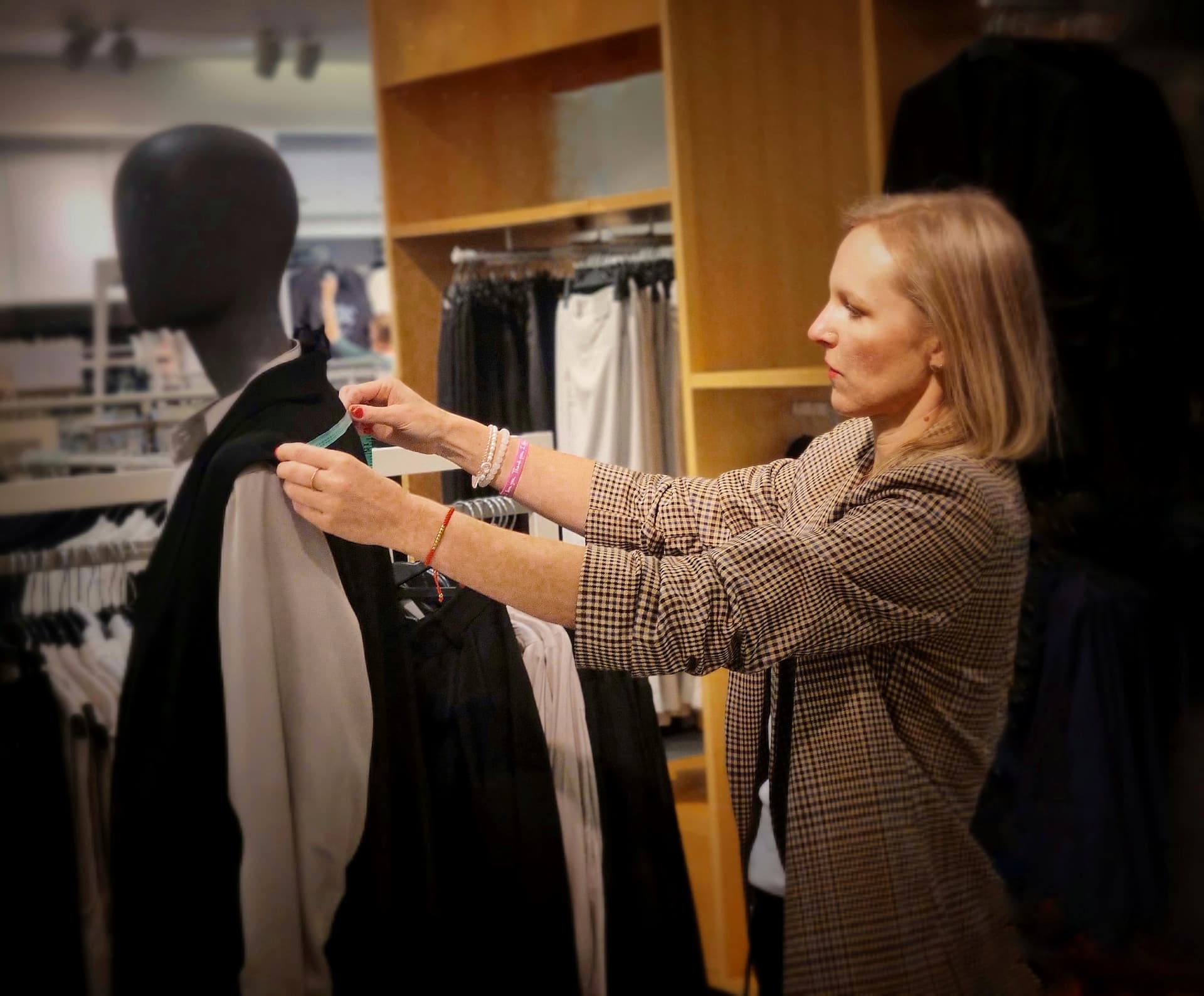 Conseillère ajustant une veste sur un mannequin dans une boutique haut de gamme