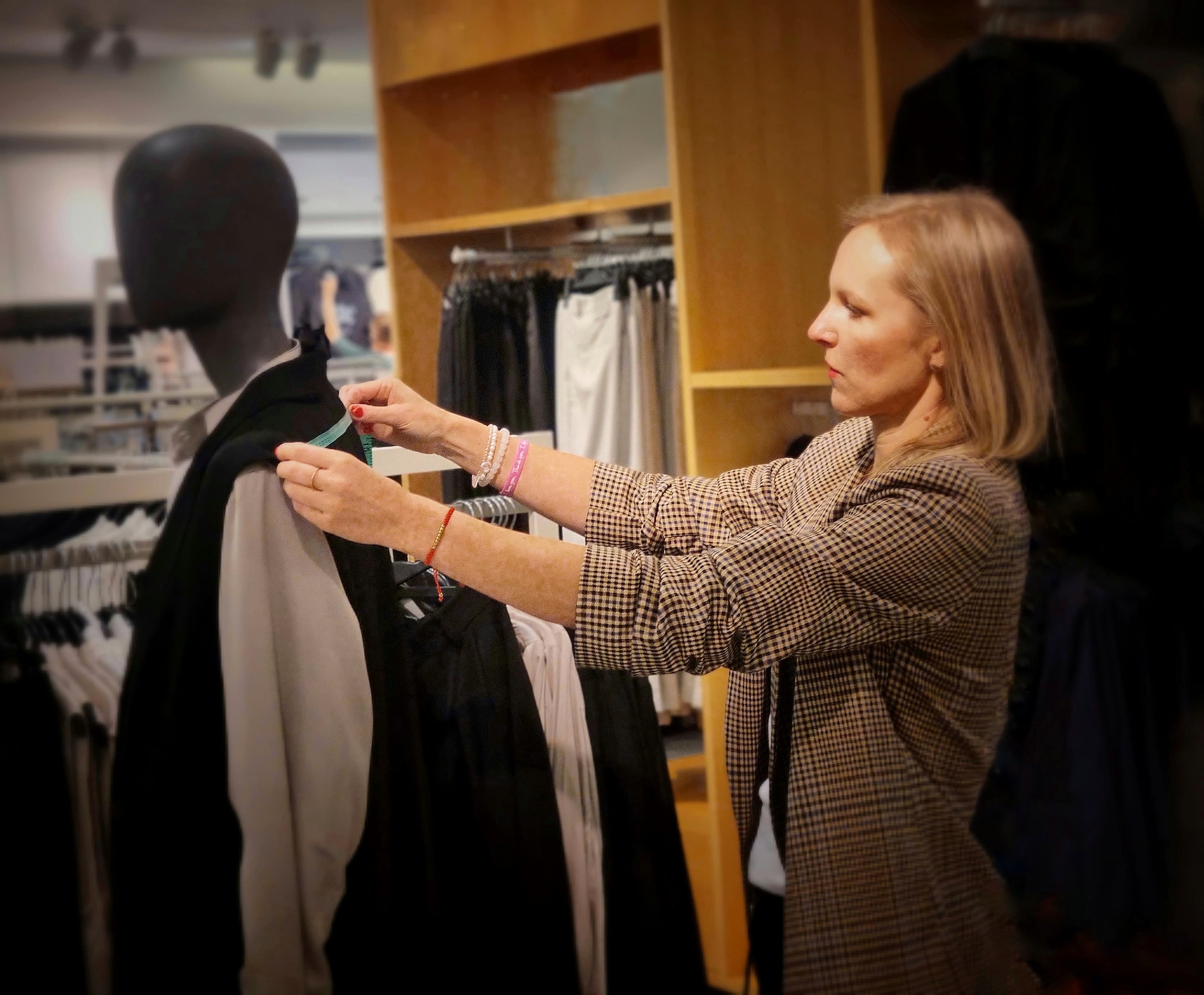 Conseillère ajustant une veste sur un mannequin dans une boutique haut de gamme