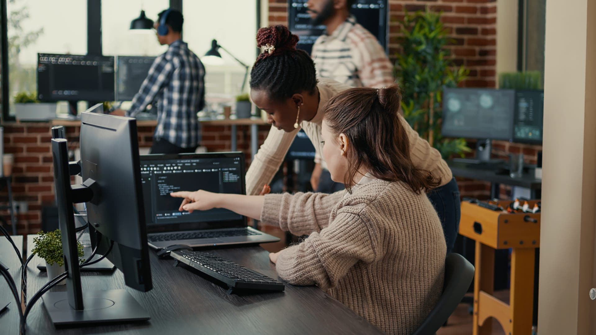 Équipe de développement en revue de code, une ingénieure pointe une ligne à l'écran