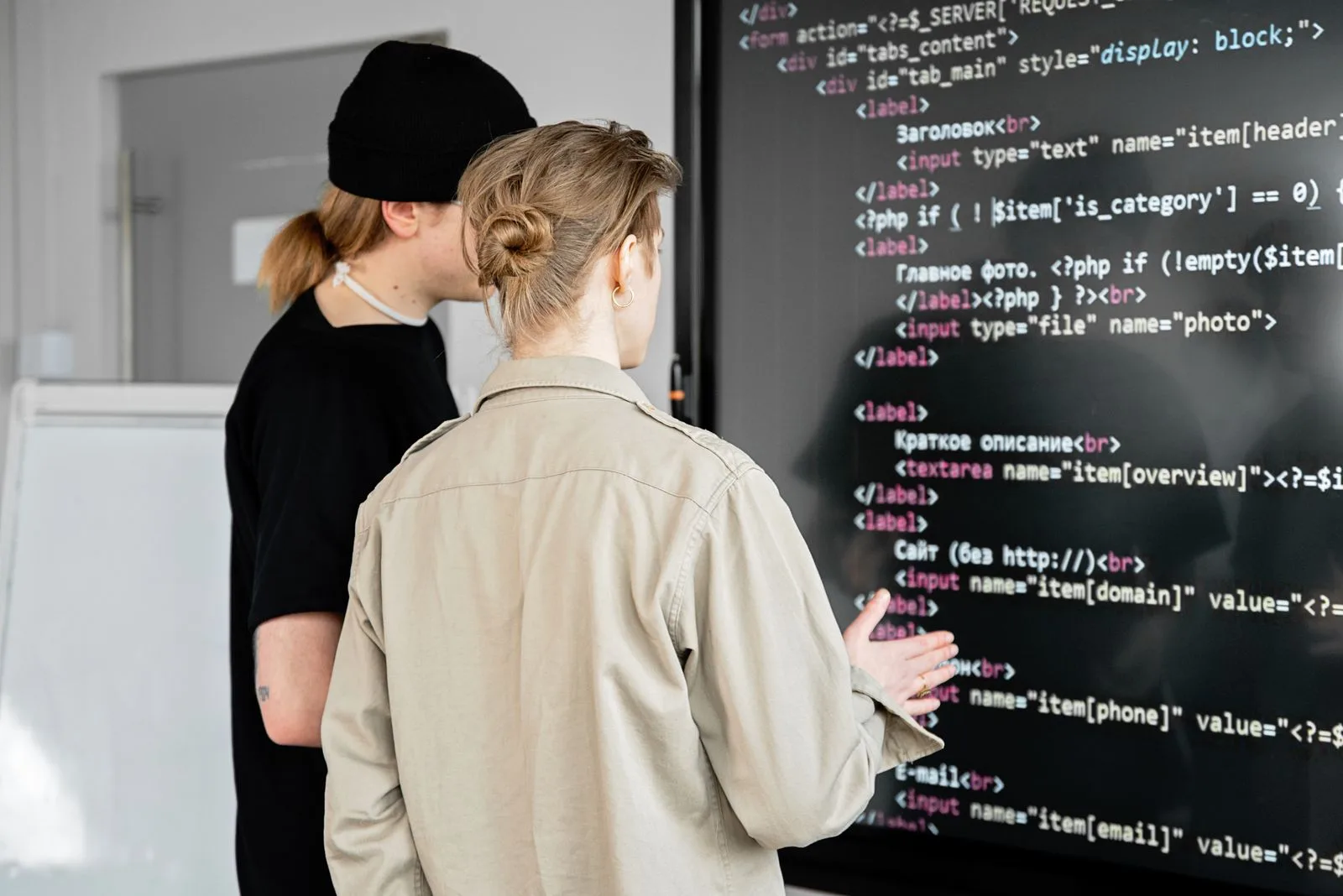 Deux développeurs examinent du code affiché sur un grand écran dans un bureau