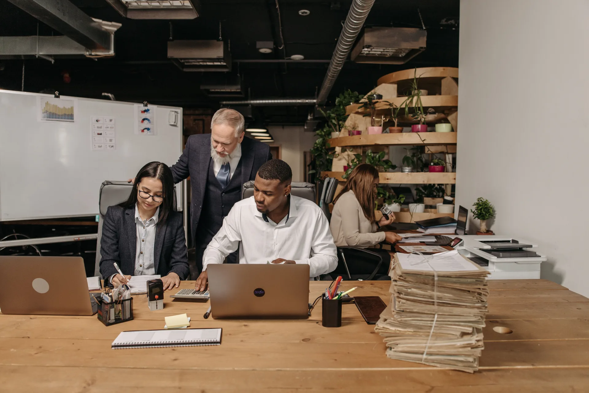 Équipe technique travaillant ensemble autour d'ordinateurs portables dans un bureau moderne