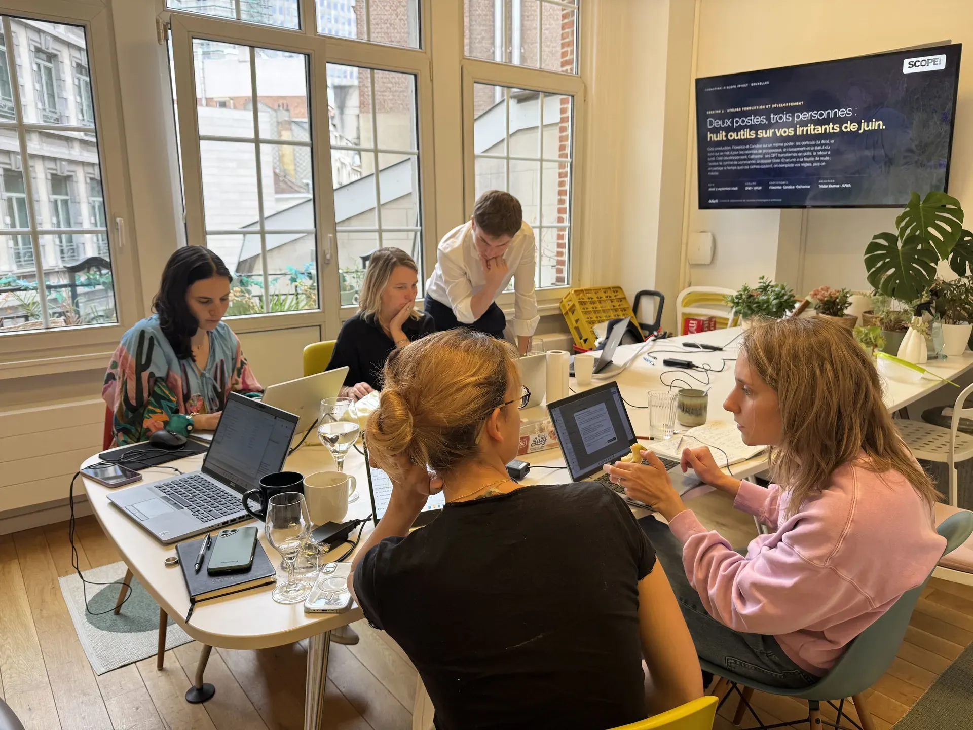 Atelier IA à Bruxelles : Tristan Dumas, de JUWA, suit l'écran d'une participante pendant que ses collègues travaillent